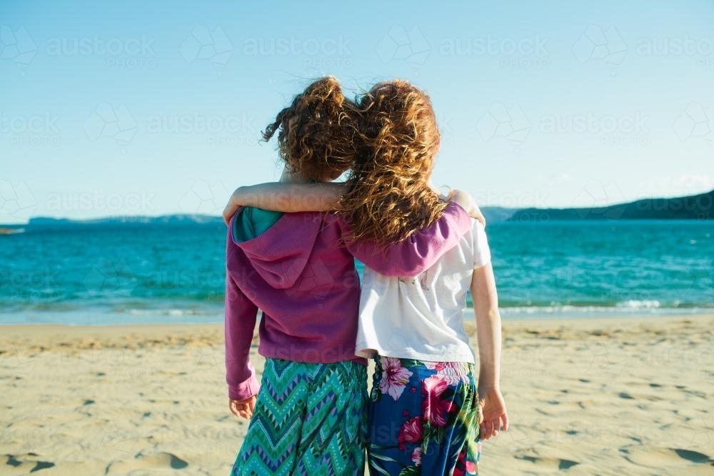 Two girls hugging at the beach - Australian Stock Image