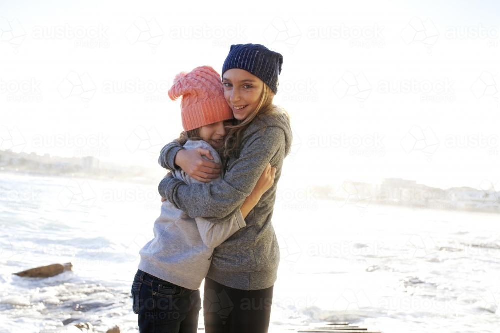 Two girls hugging by the ocean - Australian Stock Image