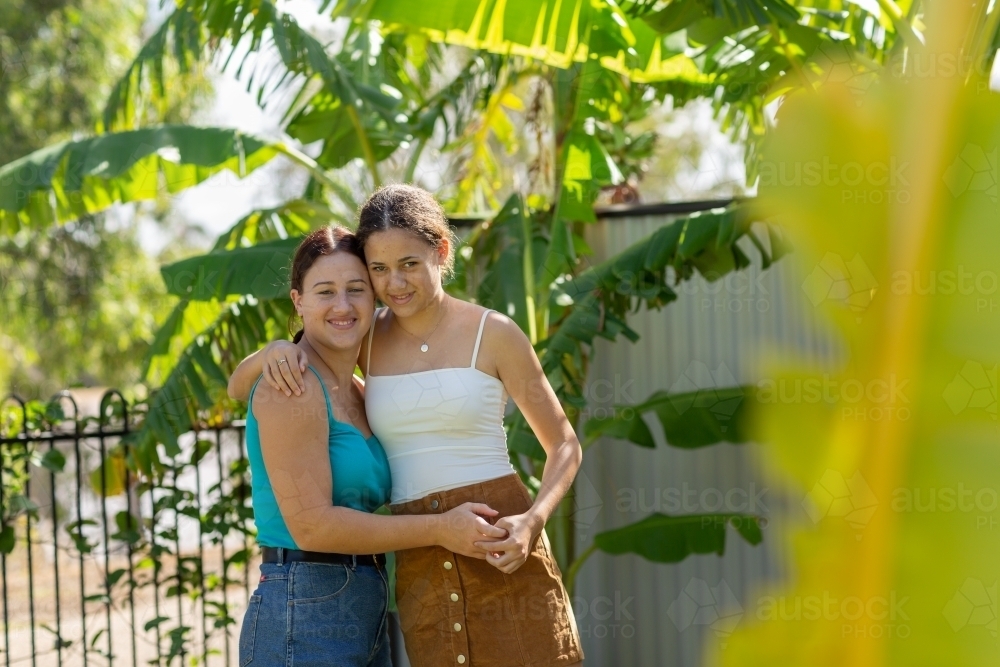 two girls in back yard with banana palms - Australian Stock Image