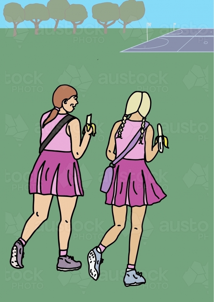 Two girls in pink sport uniforms walking across green grass to netball court eating bananas - Australian Stock Image