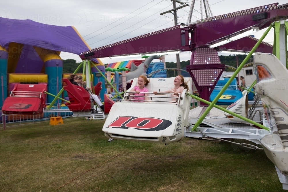 Two girls on an amusement ride at a country show - Australian Stock Image