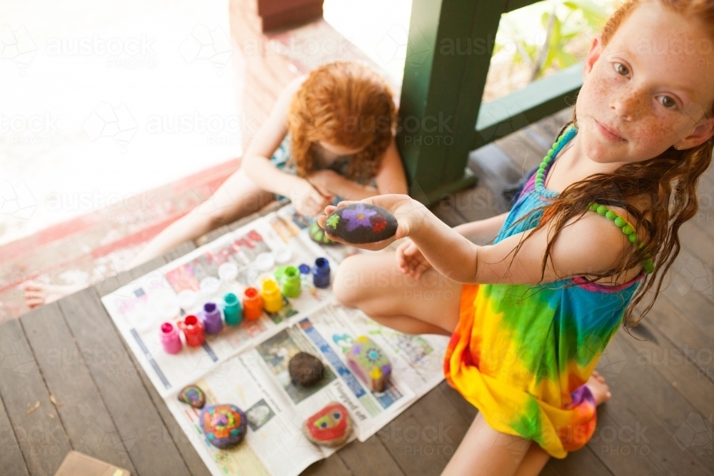 Two girls painting rocks on a verandah - Australian Stock Image