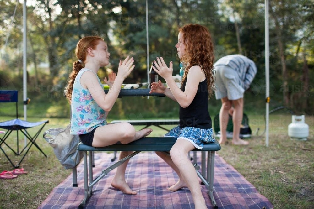Two girls playing a clapping game at a campsite - Australian Stock Image