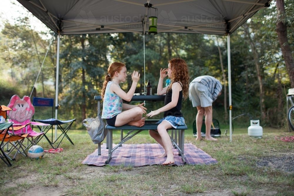 Two girls playing a clapping game at a campsite - Australian Stock Image
