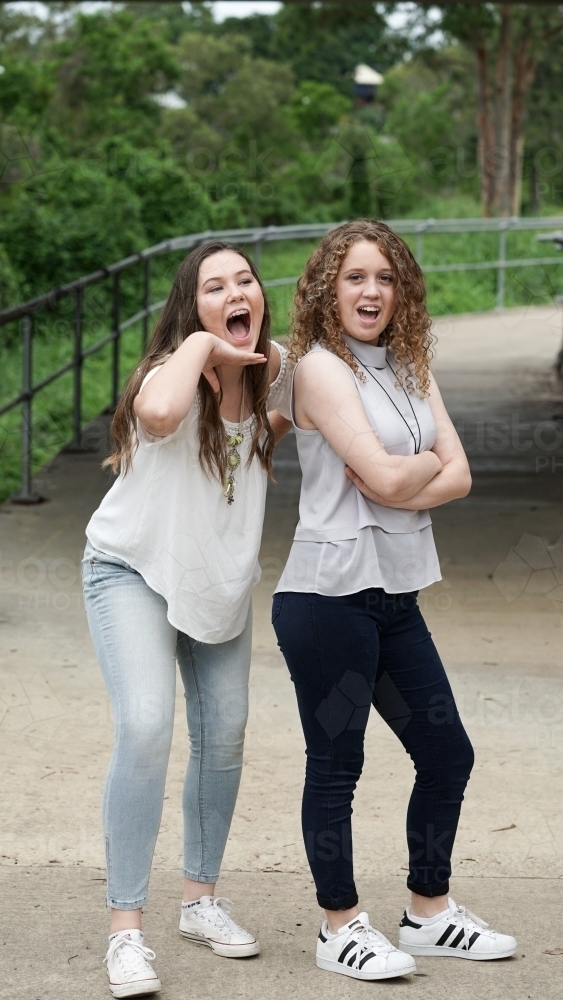 Image of Two girls standing funny poses - Austockphoto