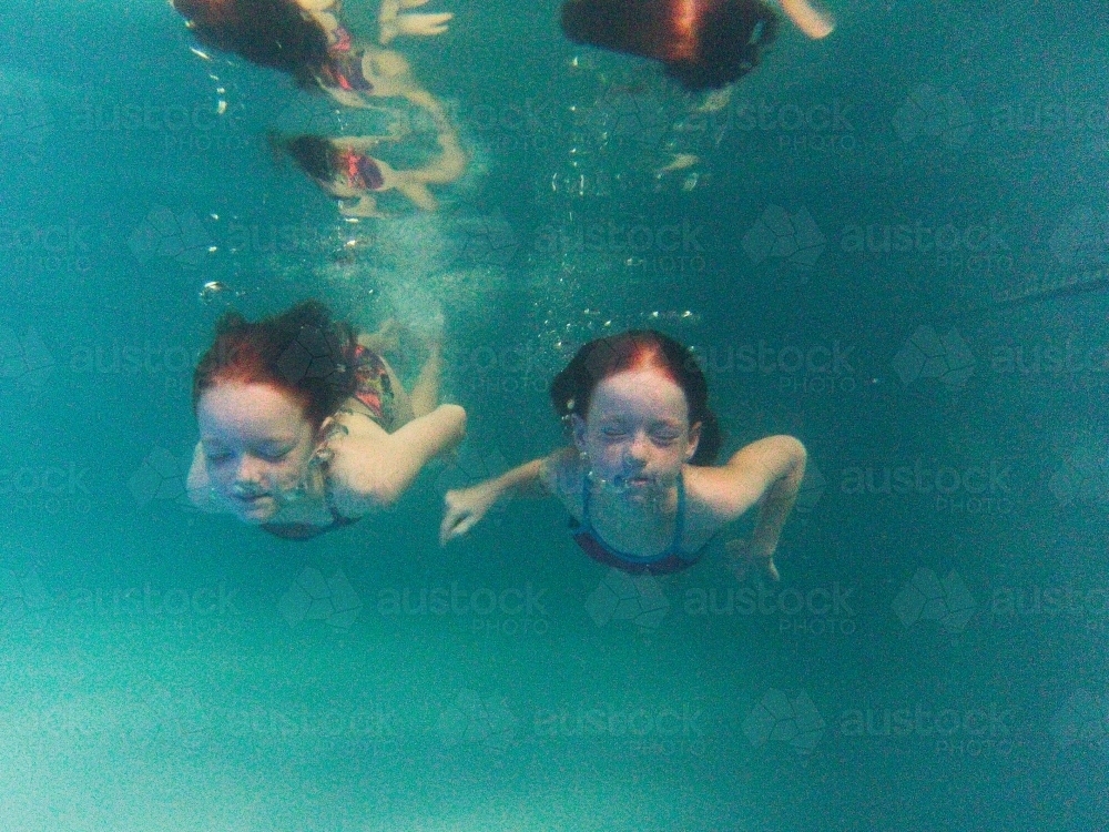 Two girls swimming underwater in a pool - Australian Stock Image