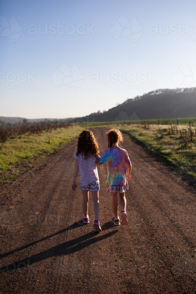 Two girls walking along a dirt road - Australian Stock Image