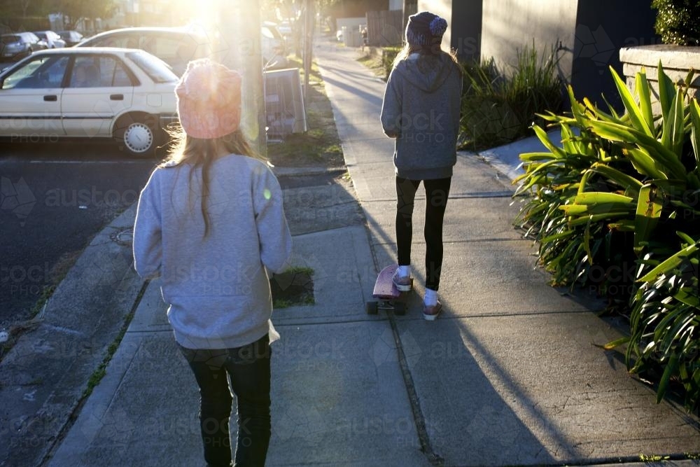 Two girls walking away on a footpath - Australian Stock Image