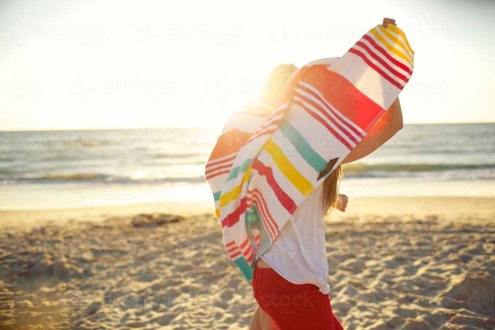 Two girls walking on the beach sharing a beach towel - Australian Stock Image