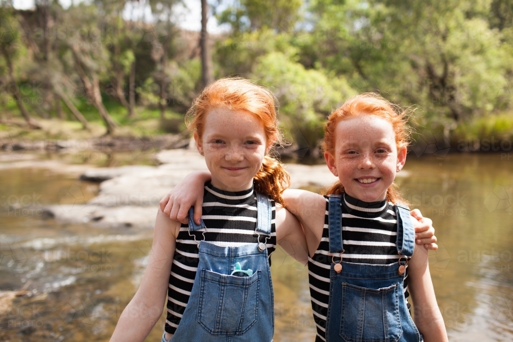 Two girls with arms around each other at the river - Australian Stock Image