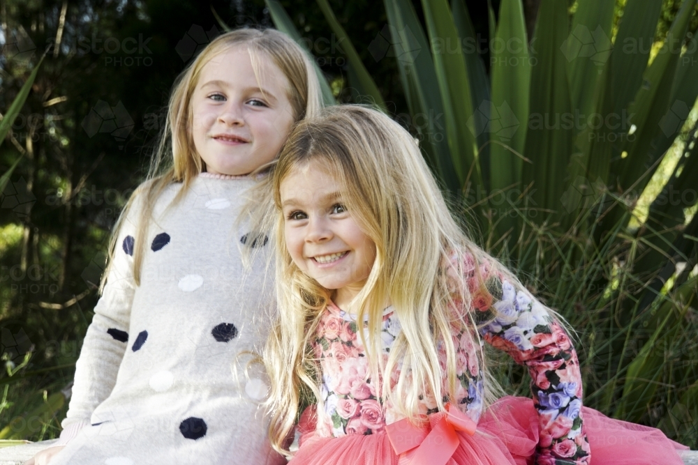 Two girls with blonde hairs playing outdoors - Australian Stock Image