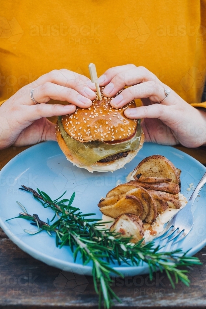 Two hands holding delicious hamburger - Australian Stock Image