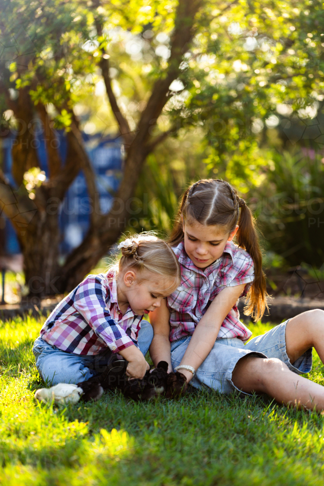Image of Two happy Aussie girls together in country backyard holding ...
