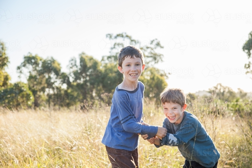 Two happy boys being kids together outdoors - Australian Stock Image
