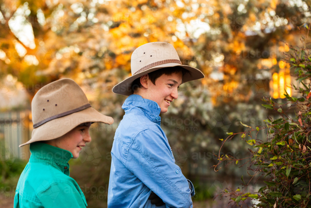 Two happy brothers in akubra hats outside in backyard of rural aussie home - Australian Stock Image