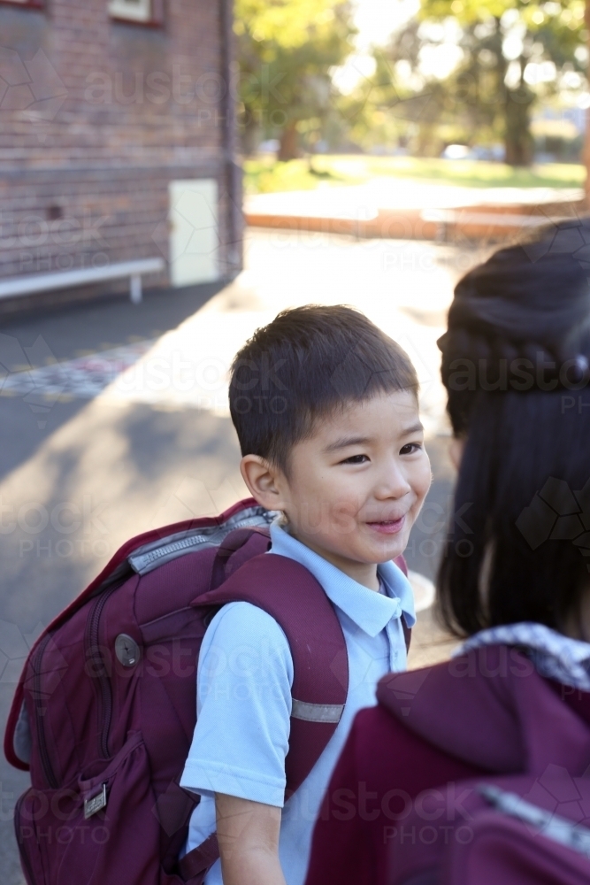 Two happy children talking in the playground at school - Australian Stock Image