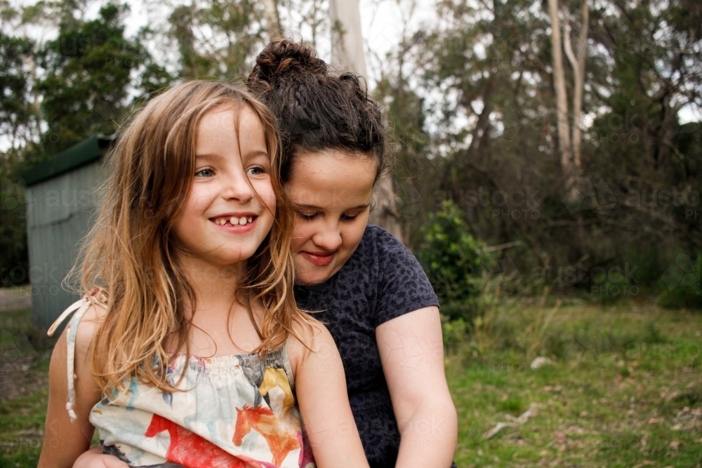 Two happy girls hugging outside in bushland - Australian Stock Image