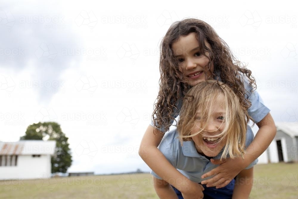 Two happy girls in school uniform playing outside - Australian Stock Image