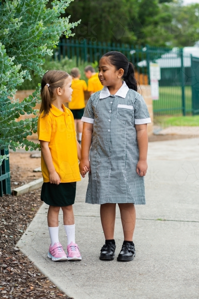 Two happy school friends walking to school together - Australian Stock Image
