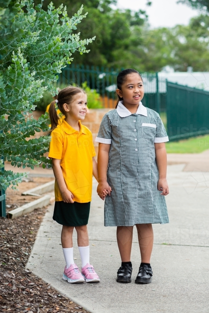 Two happy school friends walking to school together - Australian Stock Image