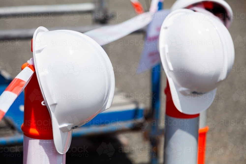 Two hard hats sitting on posts of taped off area - Australian Stock Image