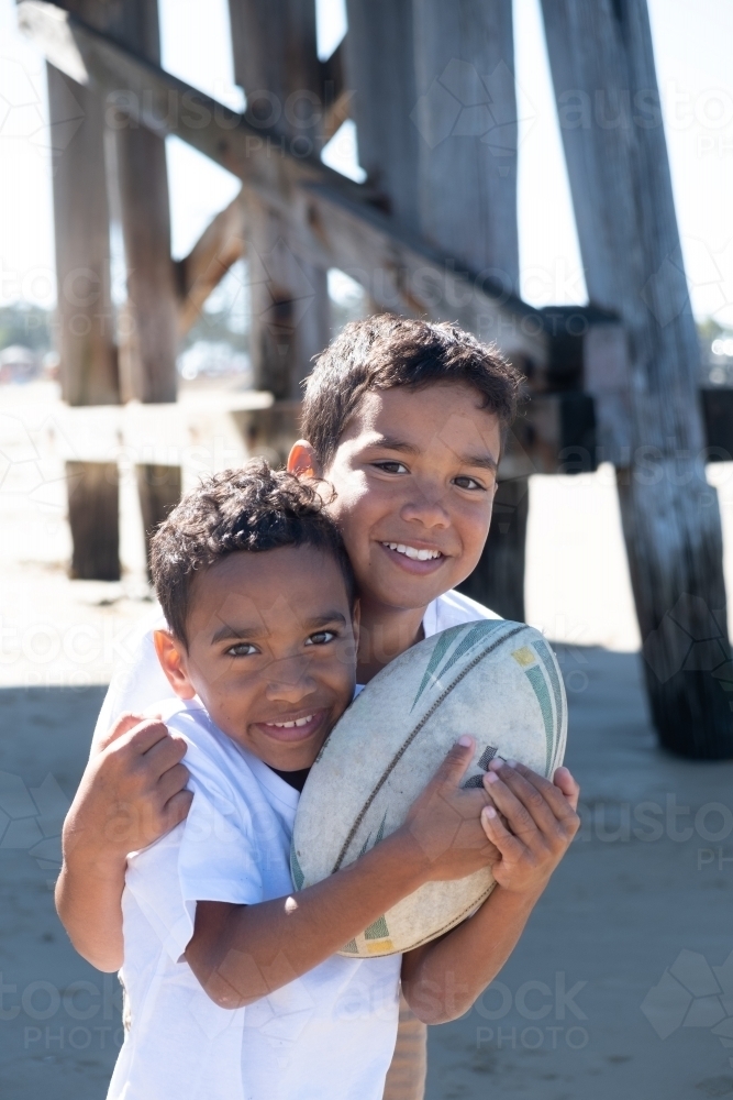 Two indigenous boys playing under a wooden pier - Australian Stock Image