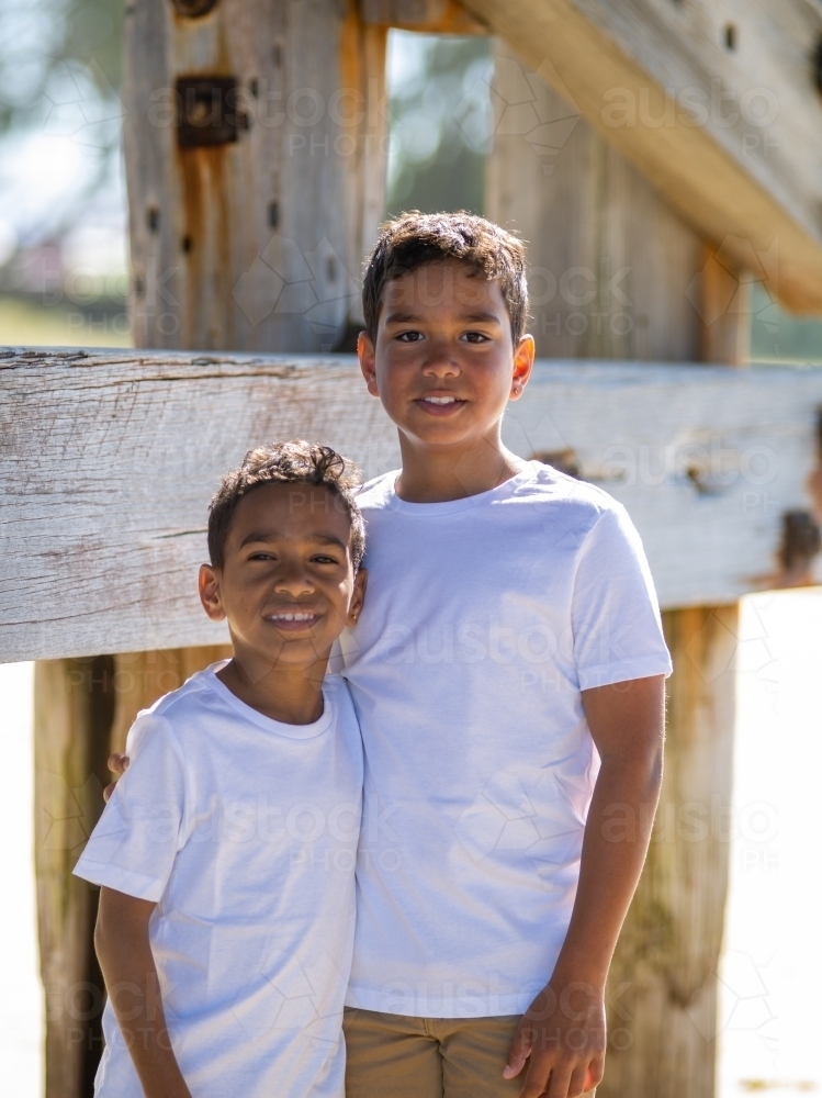 Two indigenous boys standing next to a timber house frame - Australian Stock Image