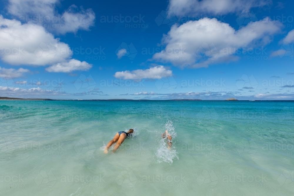 two kids diving into the shallows at the seaside - Australian Stock Image