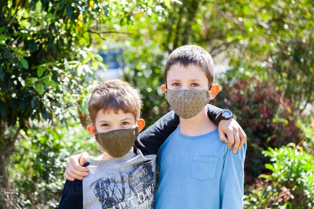Two kids from the same household wearing face masks during the coronavirus pandemic - Australian Stock Image