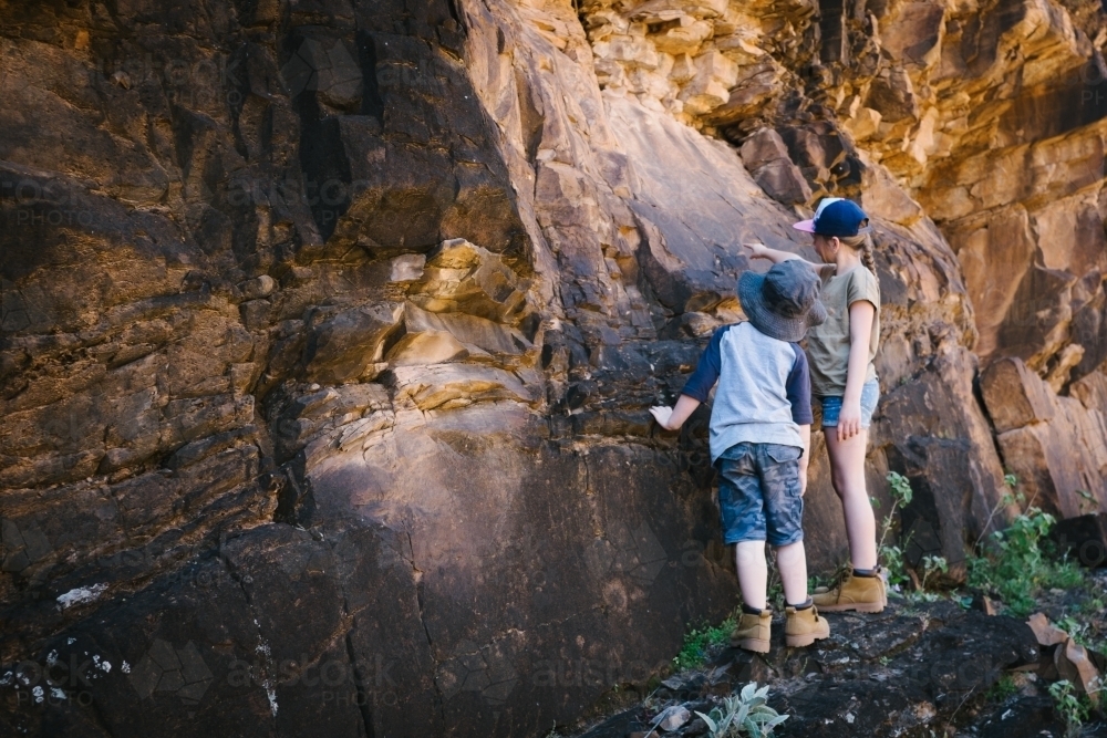 Two kids inspecting rocks during a trek through the Flinders Ranges - Australian Stock Image