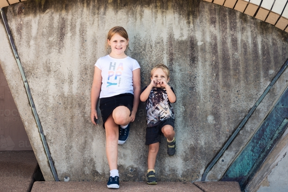 two kids posing for photos at the base of sydney opera house - Australian Stock Image