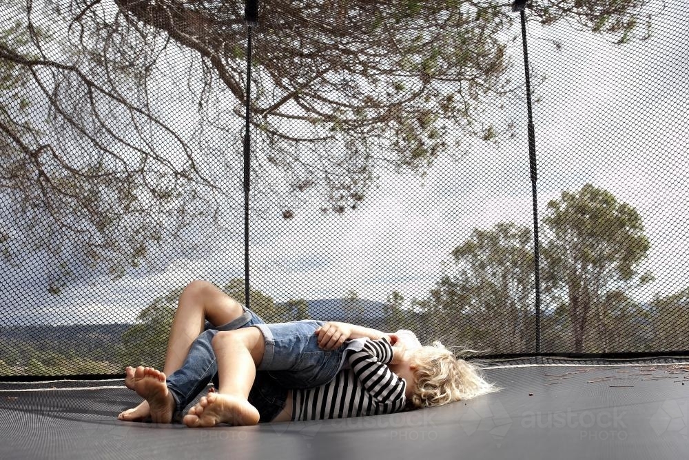Image Of Two Kids Rolling Around Wrestling On Trampoline In