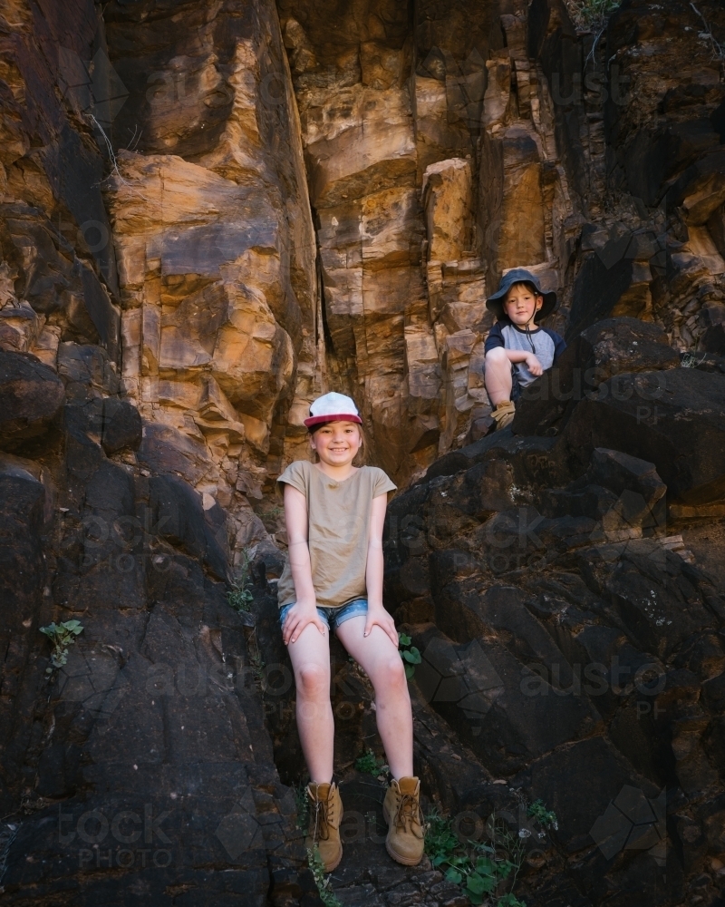 Two kids sitting on rocks during a trek through the Flinders Ranges - Australian Stock Image