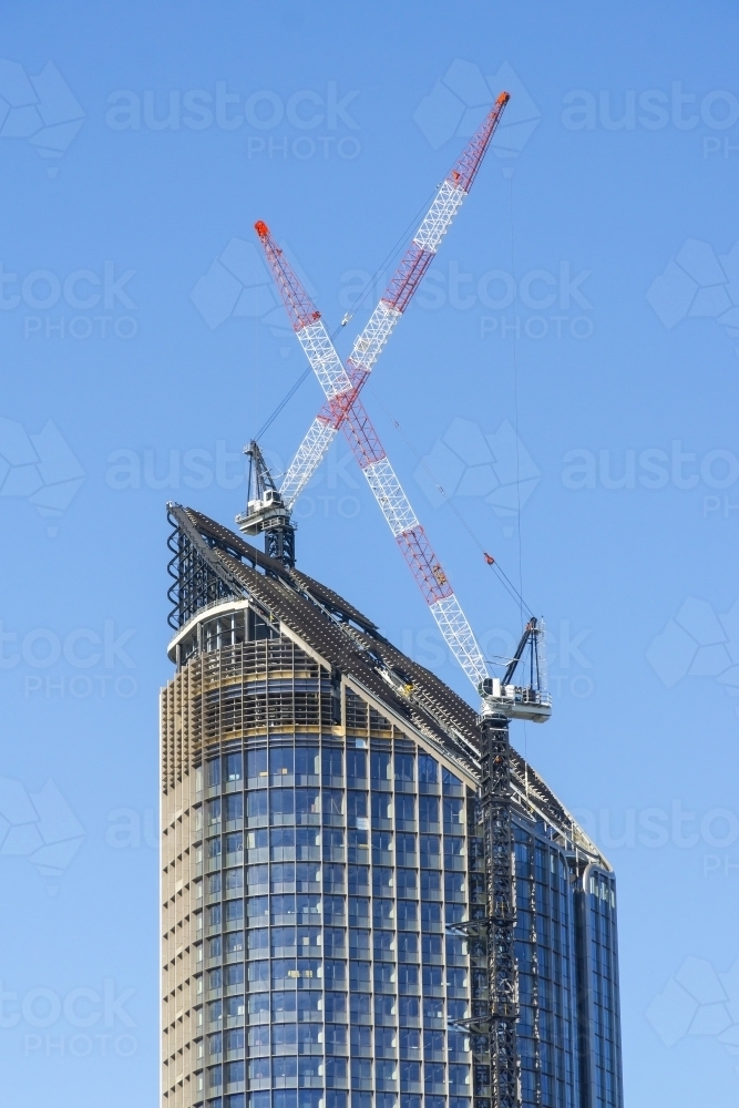 Two large cranes on the top of a city skyscraper - Australian Stock Image