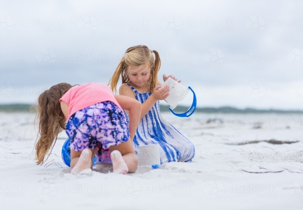 Two little girls building sandcastles on the beach - Australian Stock Image
