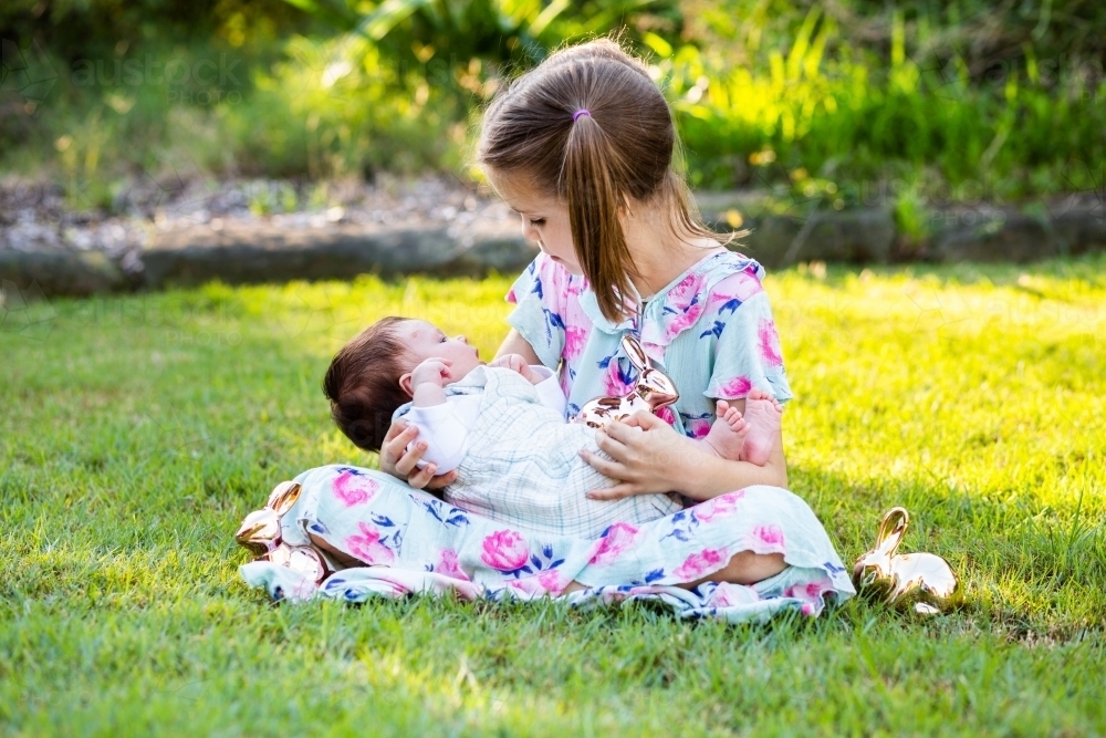 Two little girls cuddling outside with Easter rabbits - Australian Stock Image
