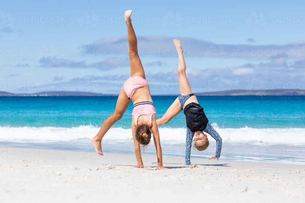 two little girls doing cartwheels on the beach - Australian Stock Image