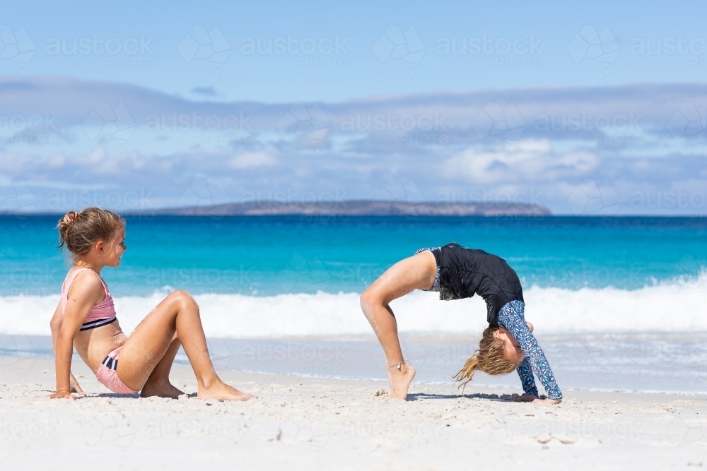 two little girls doing gymnastics on the beach - Australian Stock Image
