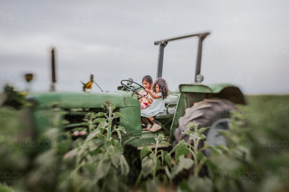 Two little girls on a green tractor - Australian Stock Image