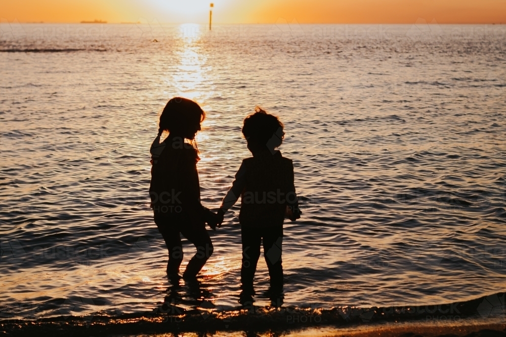 Two little girls silhouette at the beach - Australian Stock Image
