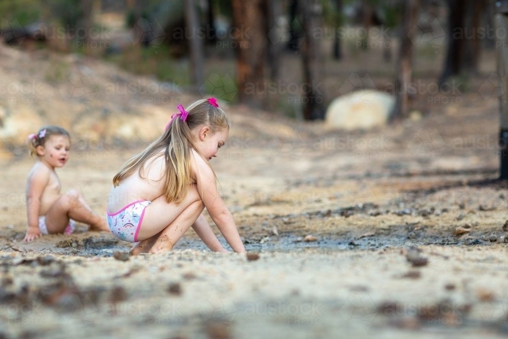 Two little kids playing in a muddy puddle - Australian Stock Image