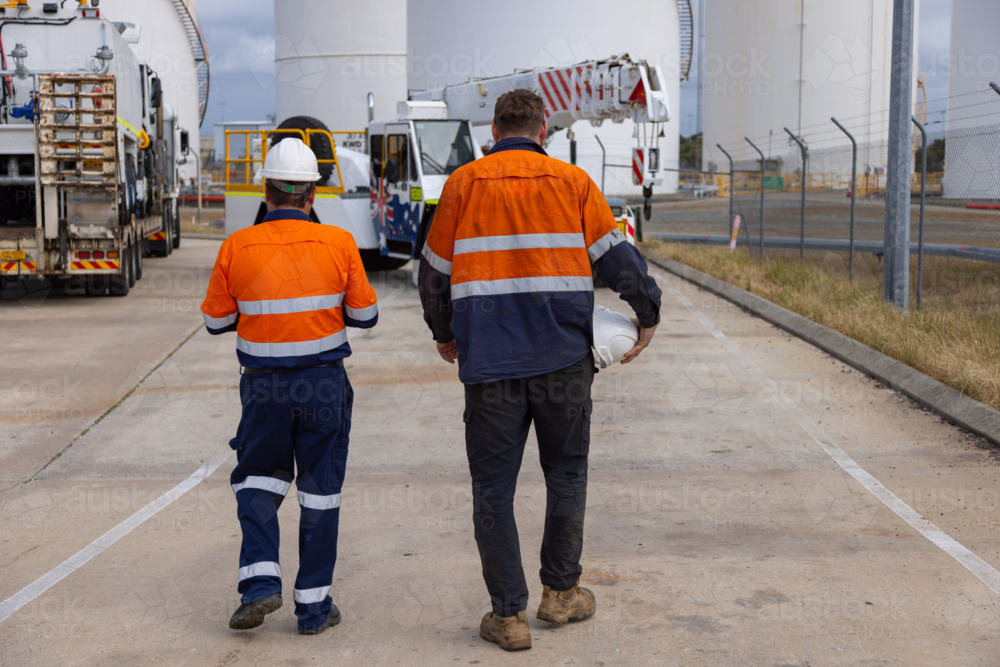 Two male workers in high visibility clothing walking towards the truck. - Australian Stock Image