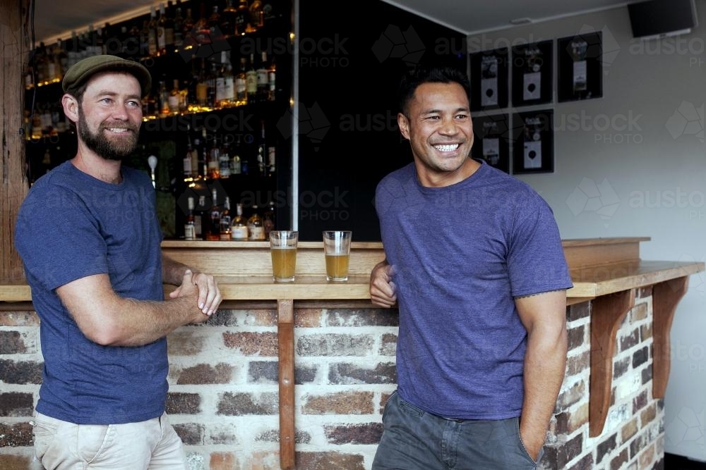 Two mates standing at the bar having a drink at local craft beer pub - Australian Stock Image