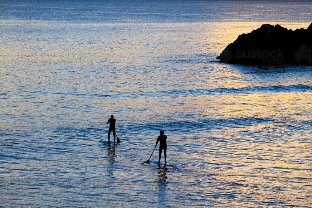 Two mature men paddleboard SUP near Norries Head at Cabarita Beach, NSW - Australian Stock Image