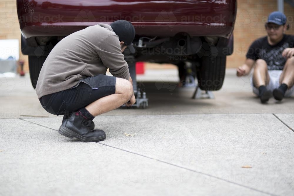 Two mechanics inspect a vehicle. - Australian Stock Image
