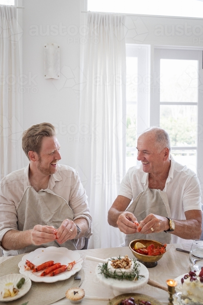 Two men deveining prawns at dinner table - Australian Stock Image