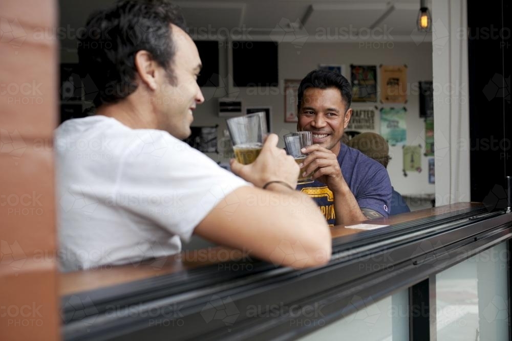 Two men enjoying drink at local craft beer bar through the window - Australian Stock Image