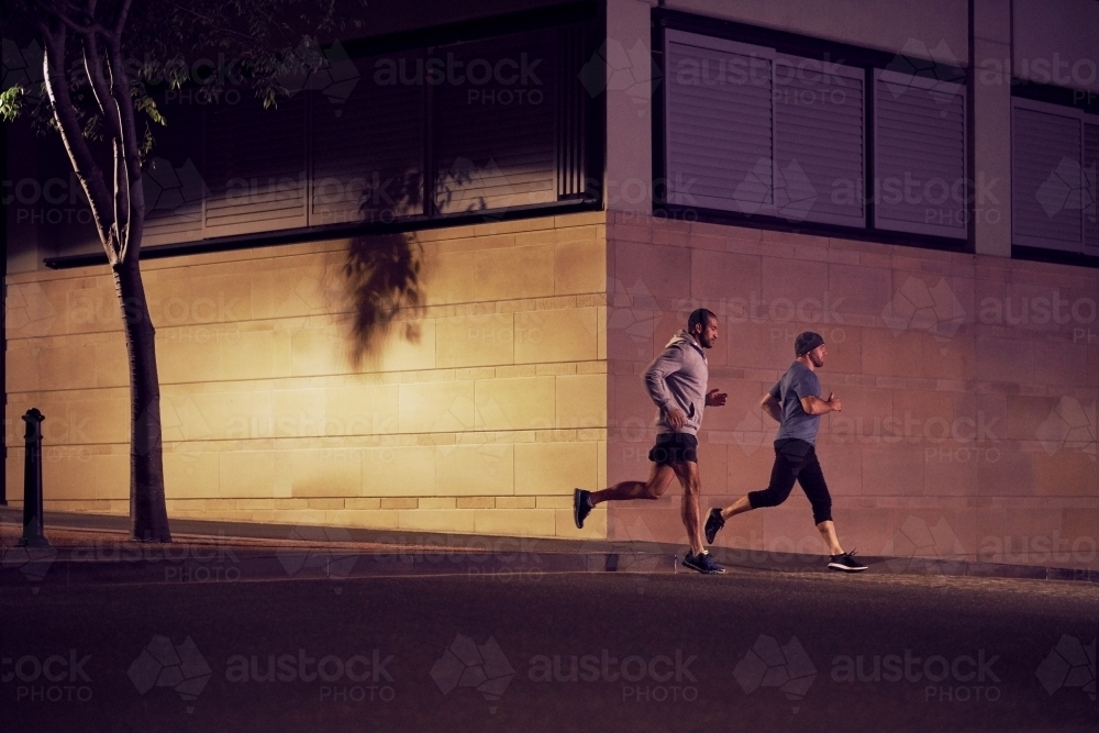 Two men fitness training in urban city at night - Australian Stock Image