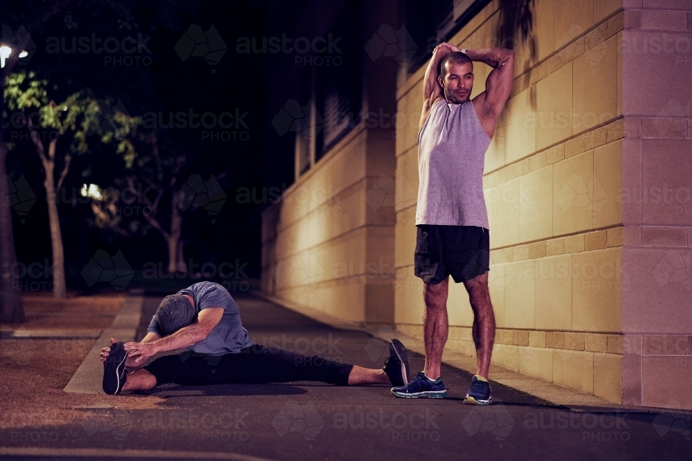 Two men fitness training in urban city at night - Australian Stock Image