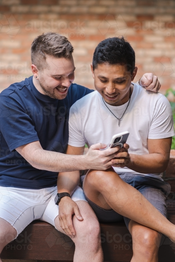 two men looking at phone screen - Australian Stock Image